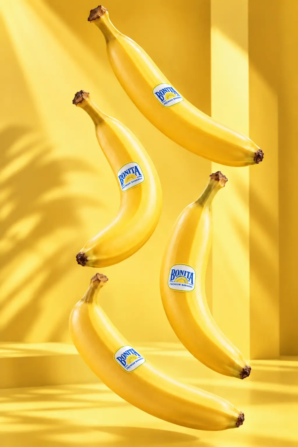 Cuatro bananos amarillos con el sticker de Bonita, flotando sobre fondo amarillo de estudio.
